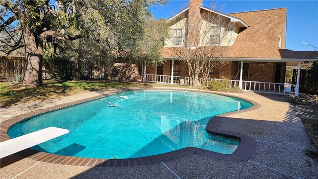 view of swimming pool featuring a patio, a diving board, a fenced in pool, and fence