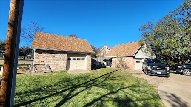 view of side of property with brick siding, a garage, a shingled roof, and a yard