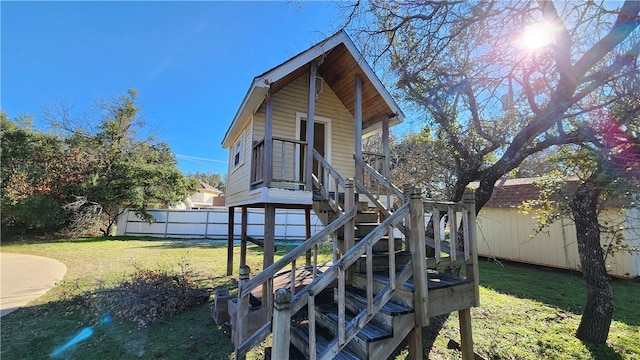 rear view of property with an outbuilding, stairway, fence, a shed, and a yard
