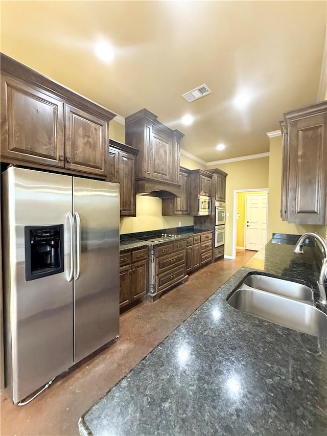 kitchen featuring visible vents, dark brown cabinets, ornamental molding, stainless steel appliances, and a sink