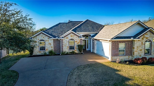 french country inspired facade with stone siding, an attached garage, a shingled roof, and a front yard