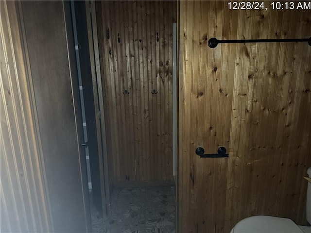 bathroom featuring wood walls and toilet