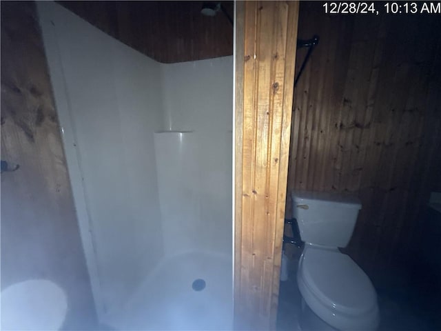 full bath with toilet, wooden walls, and a walk in shower