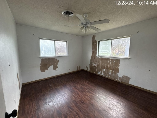 spare room with a ceiling fan, wood finished floors, visible vents, and a healthy amount of sunlight