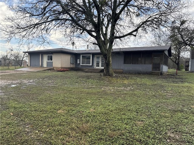view of front of house with french doors, an attached garage, a front lawn, and a sunroom