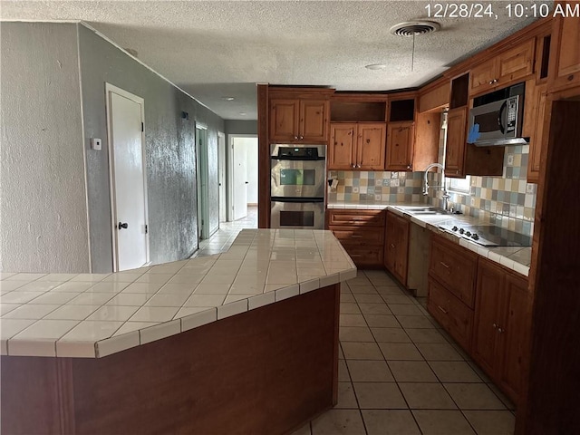 kitchen featuring visible vents, tile counters, appliances with stainless steel finishes, a textured wall, and open shelves