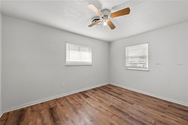 spare room featuring a wealth of natural light, ceiling fan, baseboards, and wood finished floors