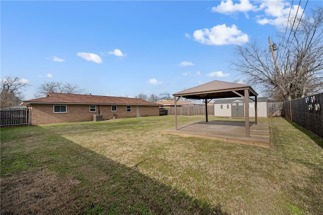 view of yard with a storage unit, an outdoor structure, central AC unit, and a fenced backyard