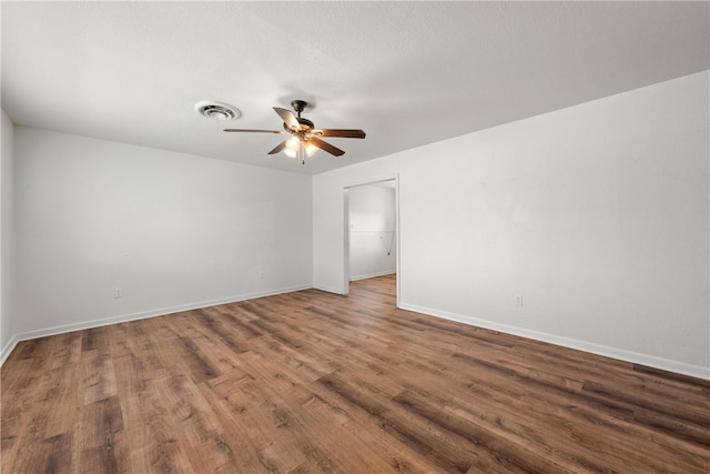 spare room with baseboards, wood finished floors, visible vents, and ceiling fan