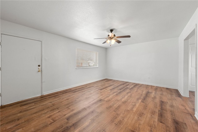 empty room featuring baseboards, a textured ceiling, a ceiling fan, and wood finished floors