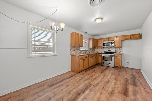 kitchen with tasteful backsplash, a chandelier, light wood-type flooring, light countertops, and stainless steel appliances