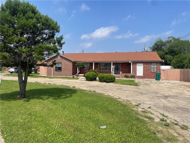 ranch-style home featuring a front lawn, fence, and brick siding