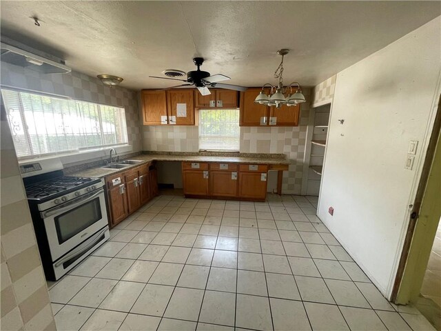 kitchen with a sink, stainless steel gas stove, a wealth of natural light, and brown cabinetry