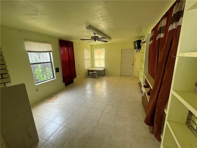 unfurnished living room featuring light tile patterned floors, a textured ceiling, and a ceiling fan