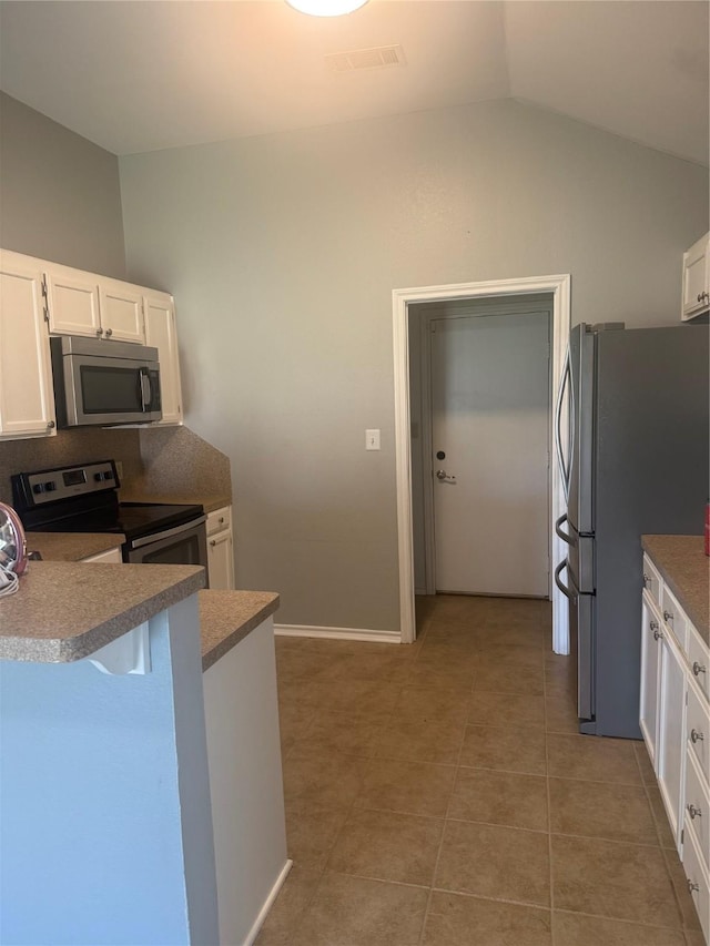 105 Wildcat Dr, Waco, TX 76705 - kitchen with stainless steel appliances, vaulted ceiling, white cabinetry, light tile patterned flooring, and a kitchen bar
