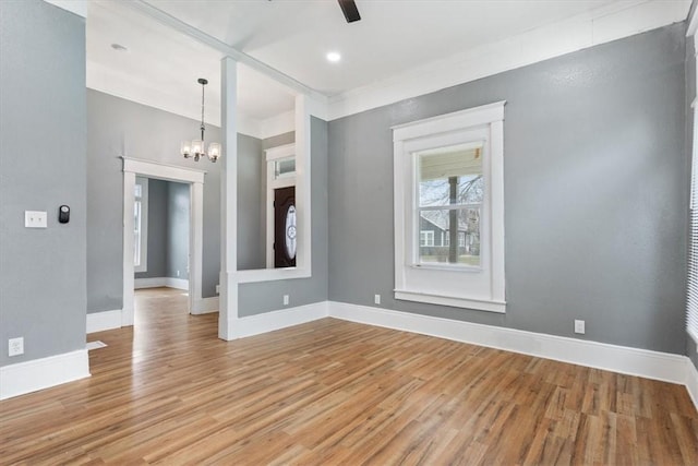 empty room with light wood-type flooring, baseboards, and ceiling fan with notable chandelier