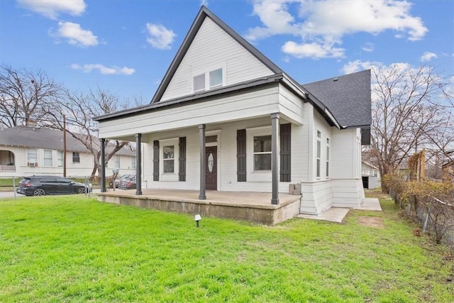 view of front facade with a front lawn, fence, a porch, and a shingled roof