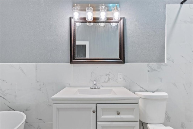 full bathroom with a soaking tub, toilet, vanity, and tile walls