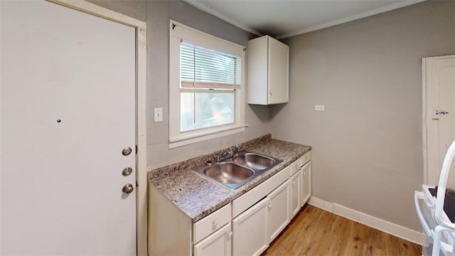 kitchen with white cabinetry, baseboards, light wood finished floors, and a sink