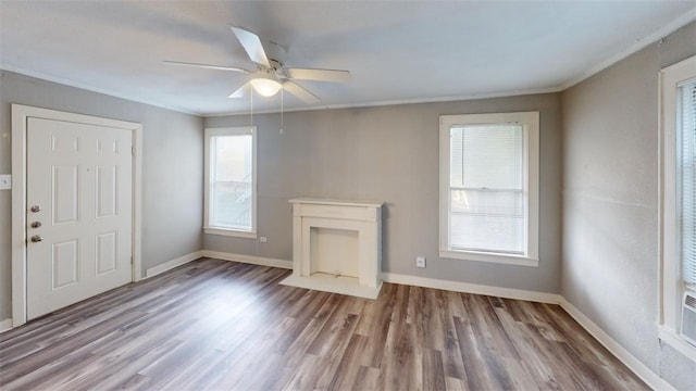 unfurnished living room with a ceiling fan, crown molding, wood finished floors, and baseboards