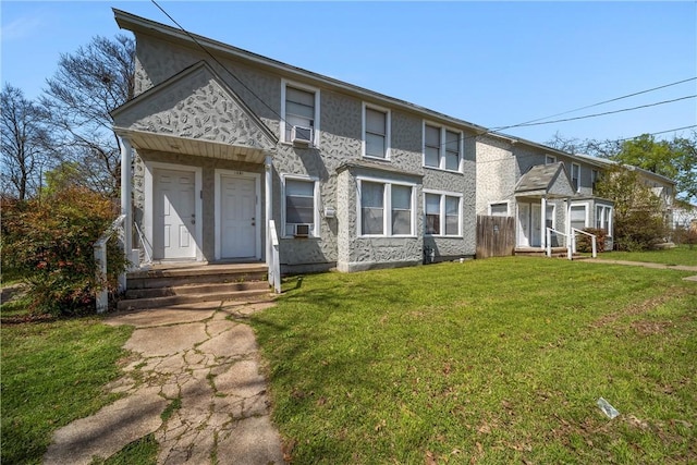 view of front of house featuring cooling unit, a front yard, and stucco siding