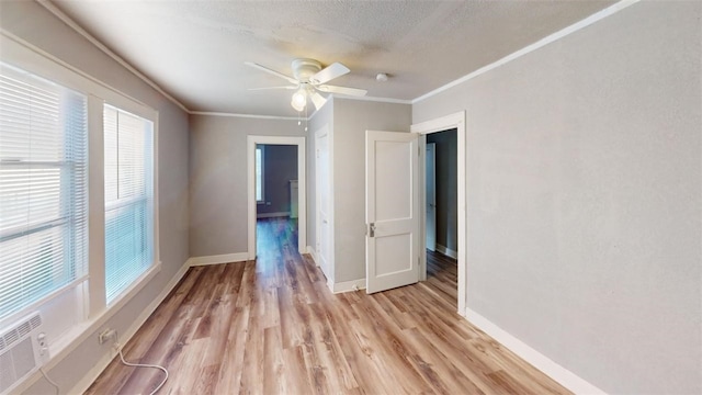 empty room featuring baseboards, a ceiling fan, crown molding, and light wood finished floors