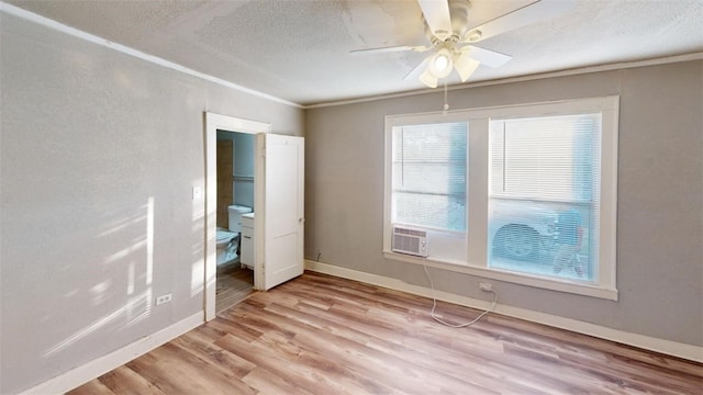 unfurnished bedroom featuring crown molding, baseboards, light wood-type flooring, cooling unit, and a textured ceiling