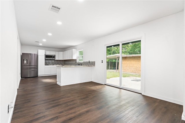 3212 Robinson Rd, Waco, TX 76706 - kitchen with visible vents, dark wood finished floors, decorative backsplash, a peninsula, and stainless steel appliances