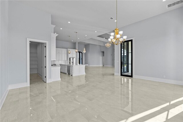 interior space with a notable chandelier, marble finish floor, baseboards, and visible vents