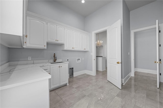kitchen featuring a sink, baseboards, light stone counters, and white cabinetry