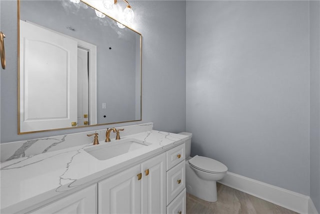 half bathroom featuring vanity, toilet, and baseboards