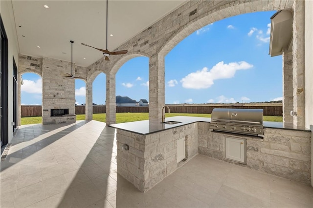 view of patio / terrace featuring area for grilling, an outdoor stone fireplace, a fenced backyard, and a grill