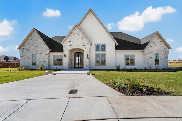 french country home with a front lawn, french doors, and stone siding
