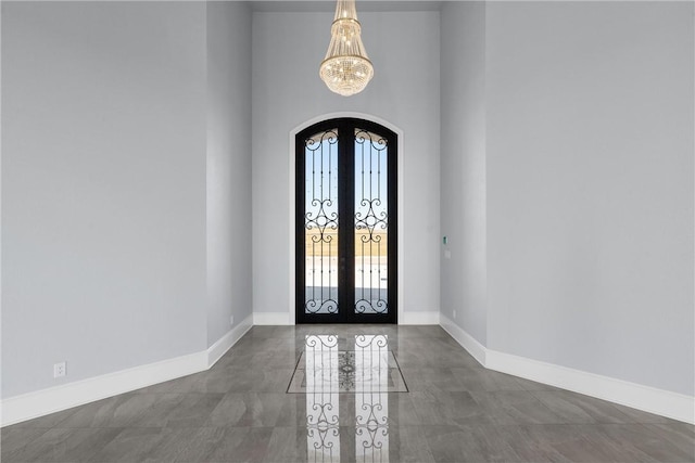 entrance foyer featuring baseboards, french doors, arched walkways, and a chandelier