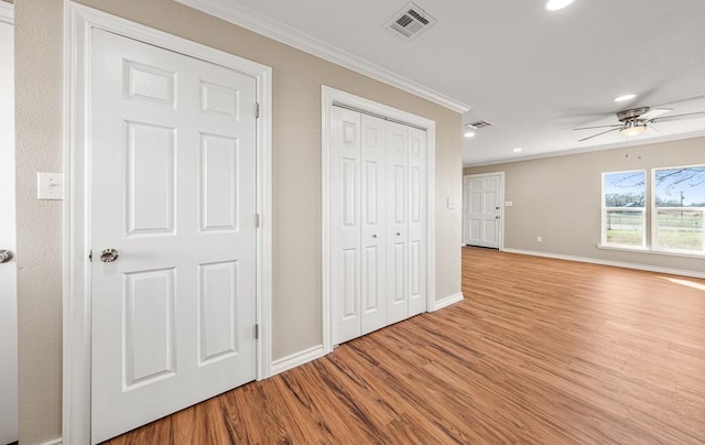 interior space with visible vents, wood finished floors, ornamental molding, and a ceiling fan