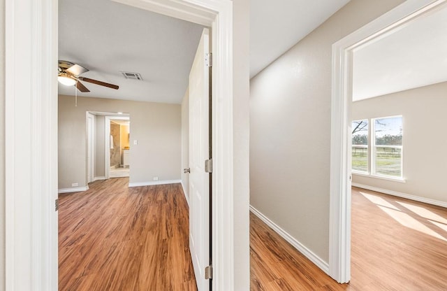 corridor featuring visible vents, baseboards, and light wood finished floors