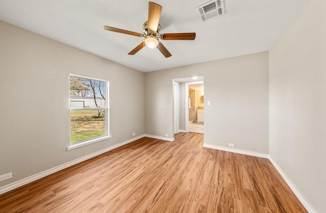 spare room with ceiling fan, visible vents, baseboards, and light wood-style flooring