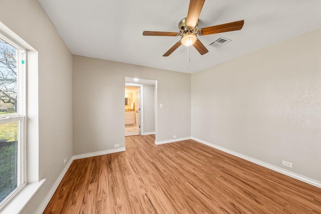 empty room featuring visible vents, baseboards, a ceiling fan, and light wood finished floors