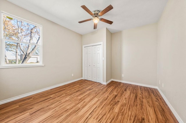unfurnished bedroom with a closet, a ceiling fan, light wood-type flooring, and baseboards