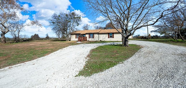 ranch-style house featuring curved driveway and a front lawn