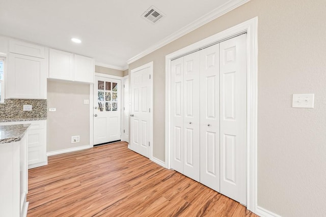 kitchen with visible vents, crown molding, light stone countertops, light wood-style flooring, and white cabinets