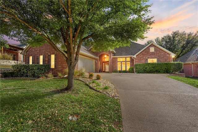 view of front of home with driveway, brick siding, a front lawn, and an attached garage