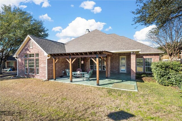 back of property featuring roof with shingles, brick siding, a patio, and a lawn