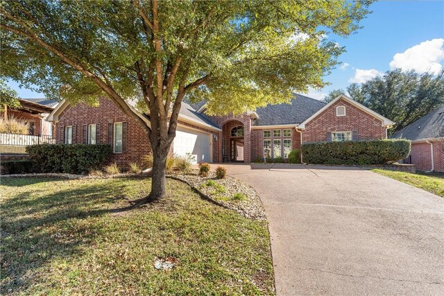 view of front of property with brick siding, driveway, a front lawn, and an attached garage