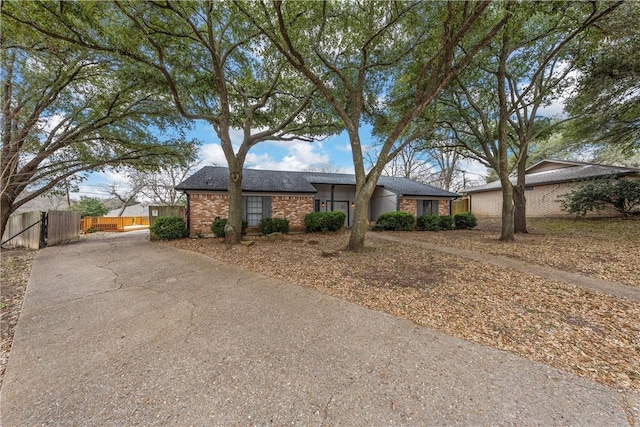 ranch-style home featuring concrete driveway, brick siding, and fence