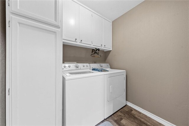 laundry room with baseboards, dark wood-type flooring, cabinet space, and washer and dryer