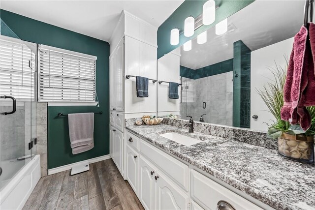 full bathroom with a tile shower, vanity, a washtub, baseboards, and wood finished floors