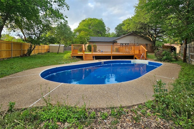 view of swimming pool featuring a lawn, a fenced in pool, a wooden deck, and a fenced backyard