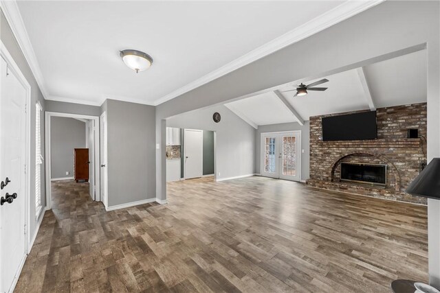 unfurnished living room with ceiling fan, baseboards, vaulted ceiling with beams, and wood finished floors