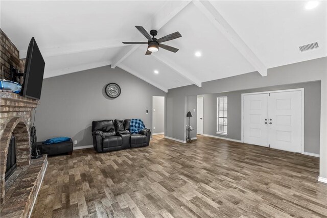 living room featuring a brick fireplace, ceiling fan, visible vents, and wood finished floors